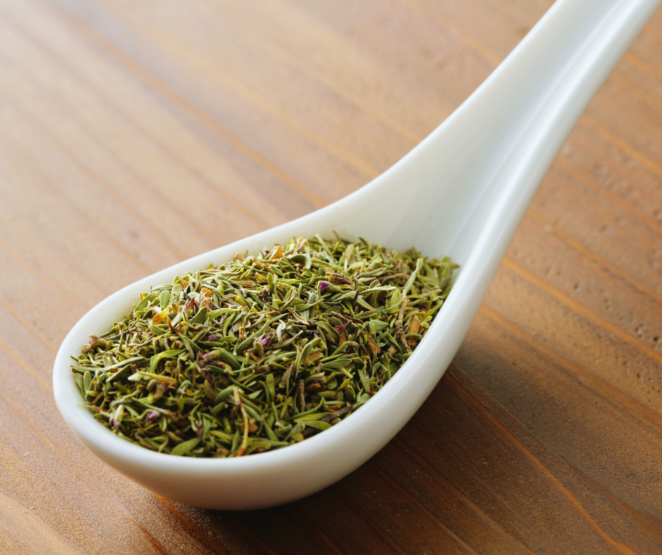 dried herbs on a ceramic spoon, on a wooden table
