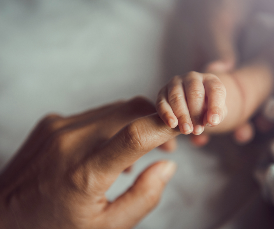 baby reaching and grabbing parents finger for safety